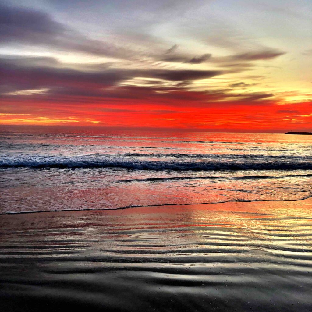 A picturesque image of the ocean with the skies alight with red colours and the water so calm and peaceful
