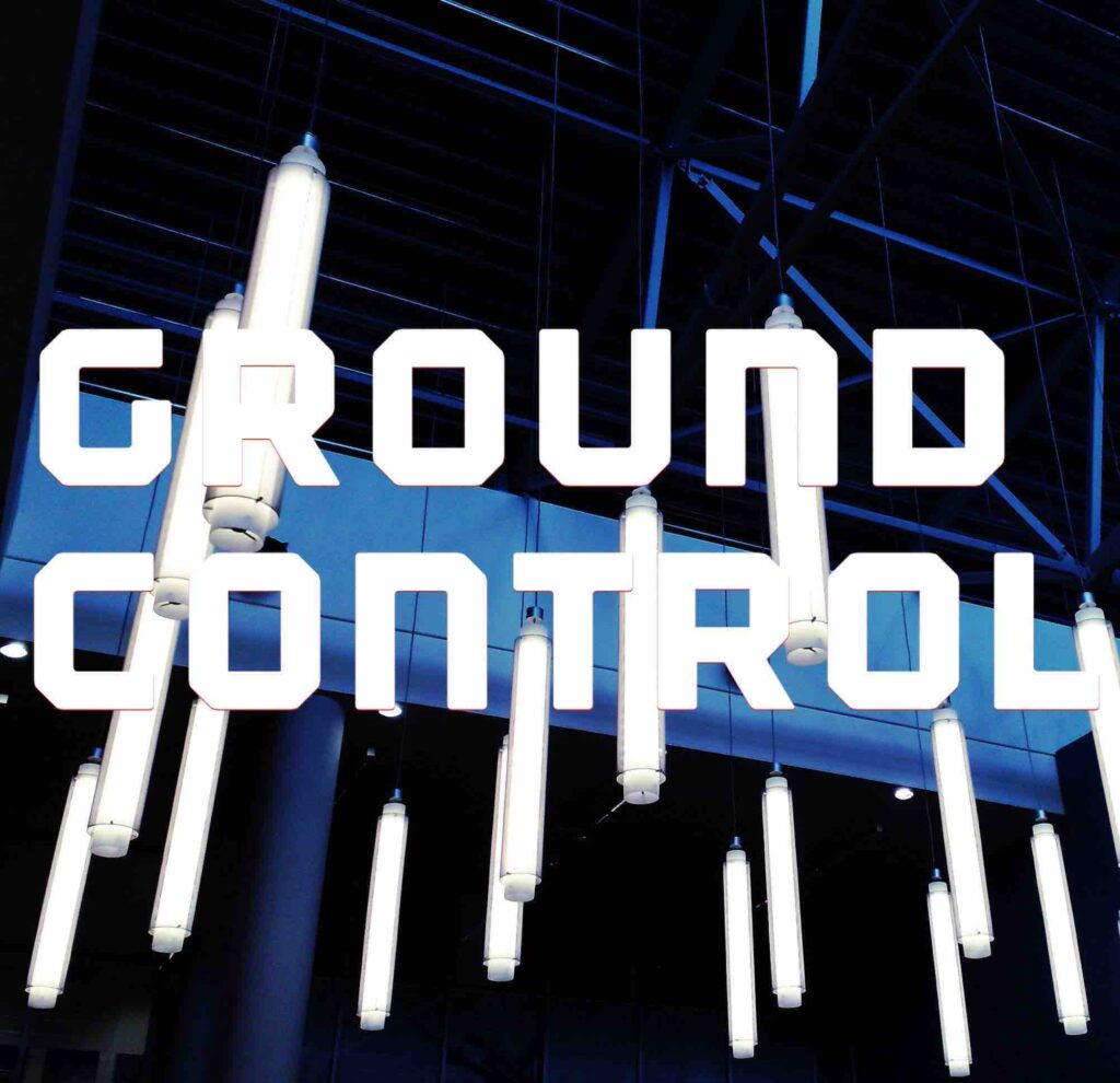 Bold letters across the image state GROUND CONTROL, over an image of white lights hanging from a large industrial ceiling