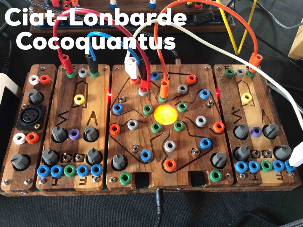 A very colourful wooden device sits on a table. Cables connect from one place to another, in red white and yellow colours. A light is on on the middle of the device. Across the top it reads Ciat-Lonbarde Cocoquantus