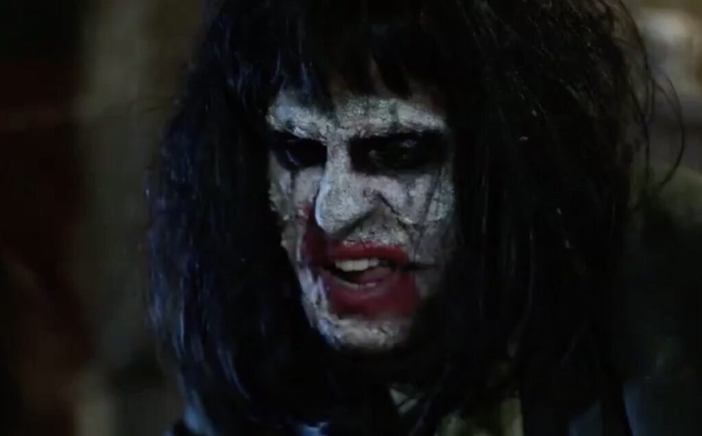 Creepy man with long black hair and distorted clown like make up, all washed out and messy. Just his face grimacing in an intimidating way