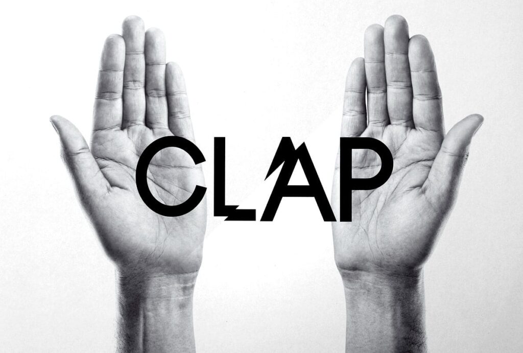 Black and white photograph of two hands, palm up, with the word CLAP in black bold letters printed across them