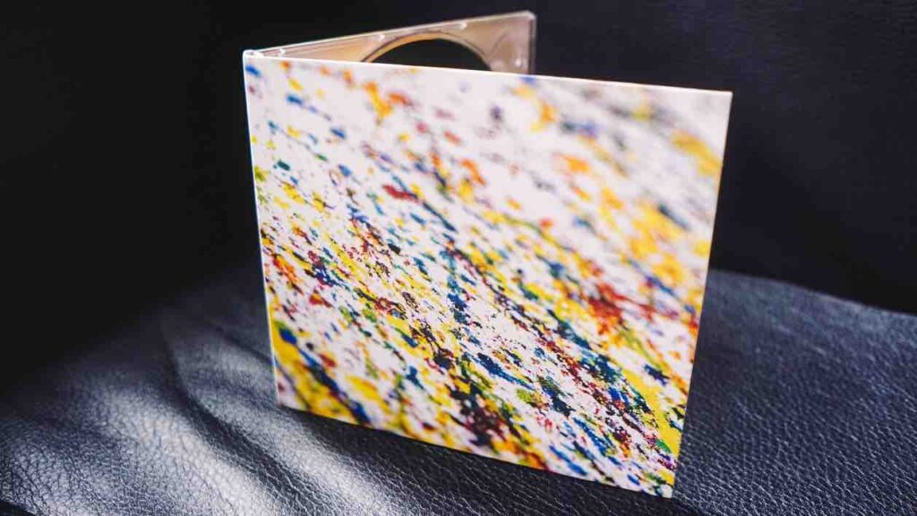 Colourful abstract cover of a compact disc, sitting on a leather sofa.