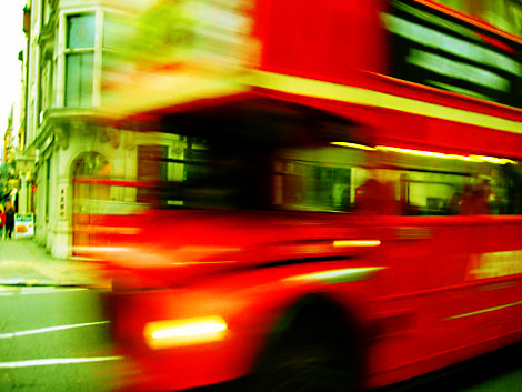 A blurry photo of a red London route master bus on a street