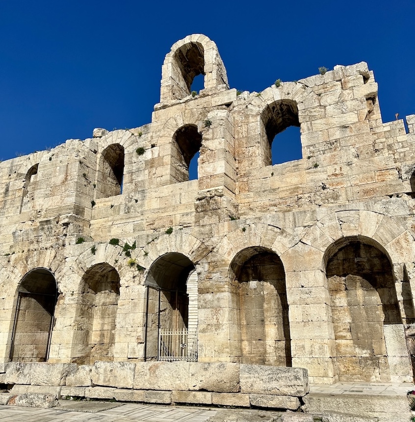 Ancient stone building with multiple arched openings under a clear blue sky