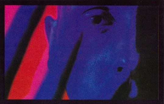 Close-up of a face illuminated with vibrant red and blue lighting, creating a colorful abstract effect