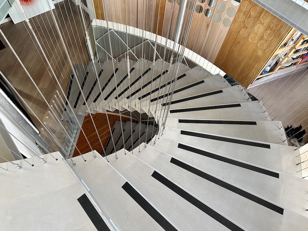 An overhead image of stainless steel staircase, with black safety strips on the lip of every step.
