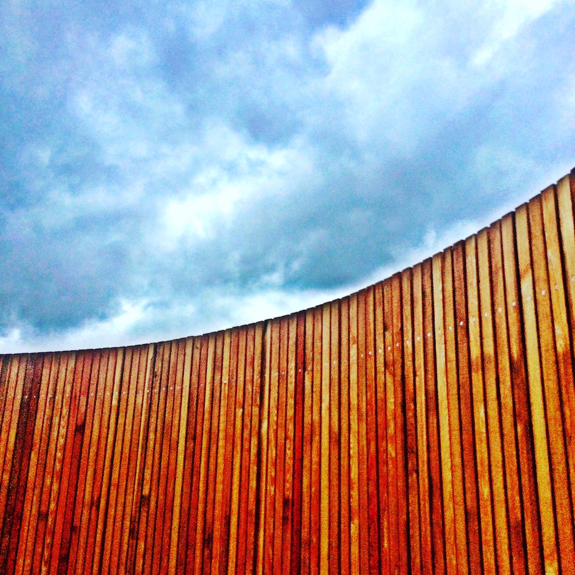 Colourful photo of blue sky cut into by a curved wooden panel
